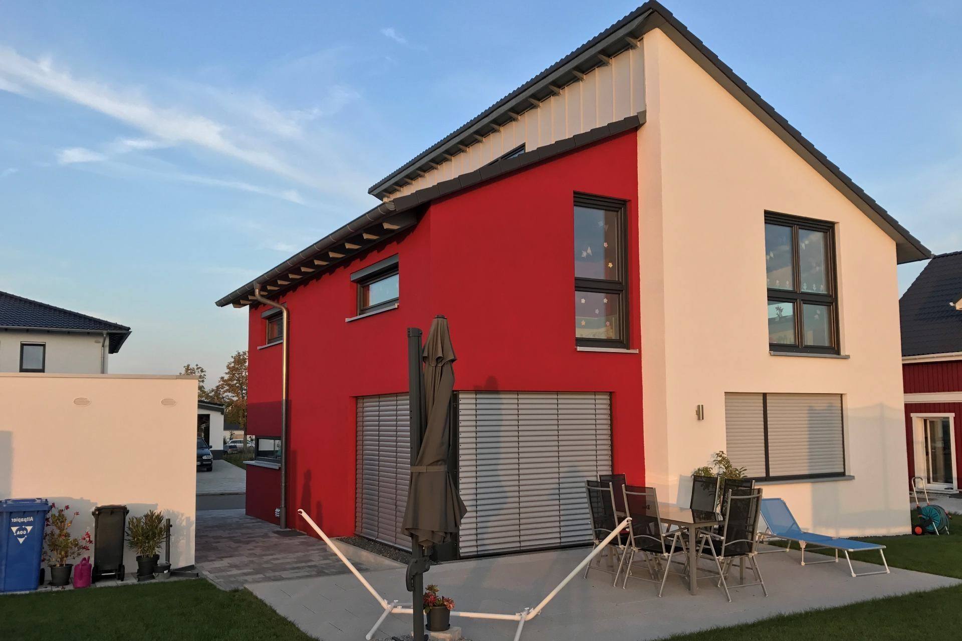 Zweigeschossiges Einfamilienhaus in Massivbauweise mit hellem Putz, Balkon und großen Fenstern